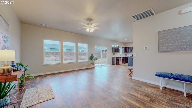 living room featuring a ceiling fan, baseboards, visible vents, and wood finished floors