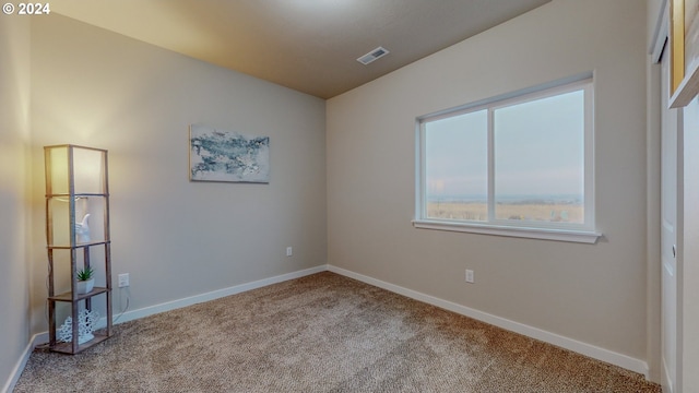 carpeted spare room with visible vents and baseboards