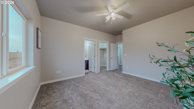 unfurnished bedroom with ceiling fan, a spacious closet, baseboards, and carpet flooring