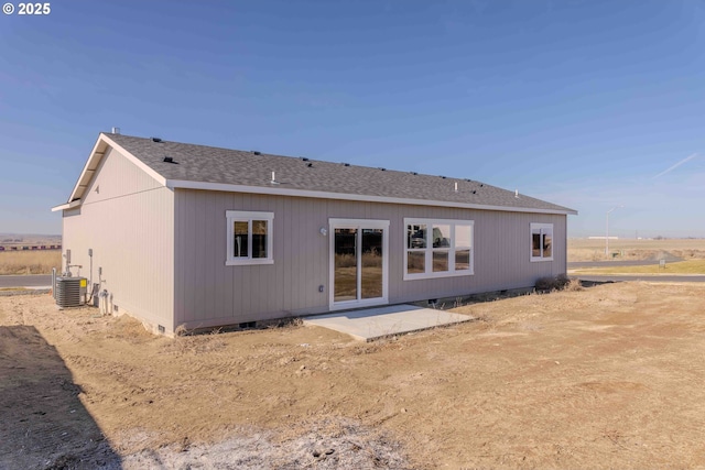 back of property with a shingled roof, cooling unit, and crawl space