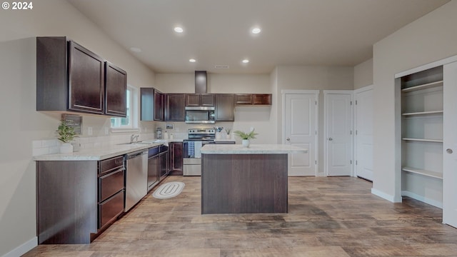 kitchen featuring a center island, appliances with stainless steel finishes, a sink, dark brown cabinetry, and light wood-type flooring