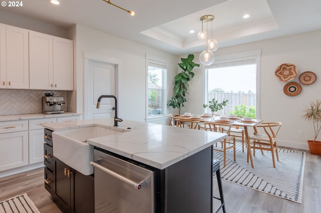 kitchen with light hardwood / wood-style flooring, dishwasher, white cabinetry, and a kitchen island with sink