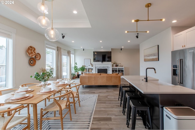 dining room with light hardwood / wood-style flooring, a tray ceiling, a healthy amount of sunlight, and sink