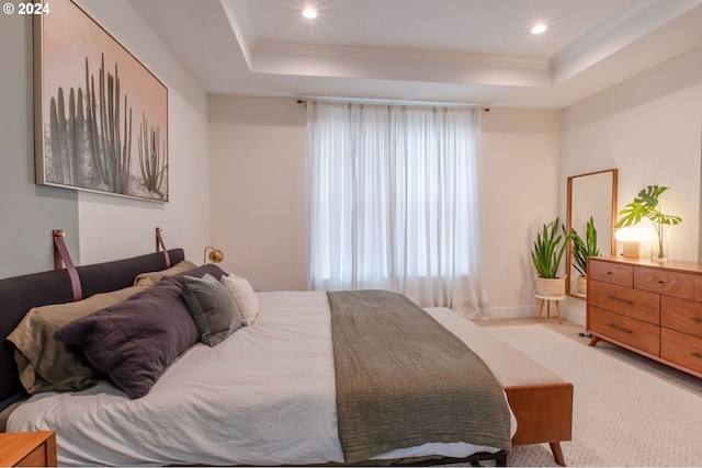 bedroom with light carpet, a tray ceiling, and ornamental molding