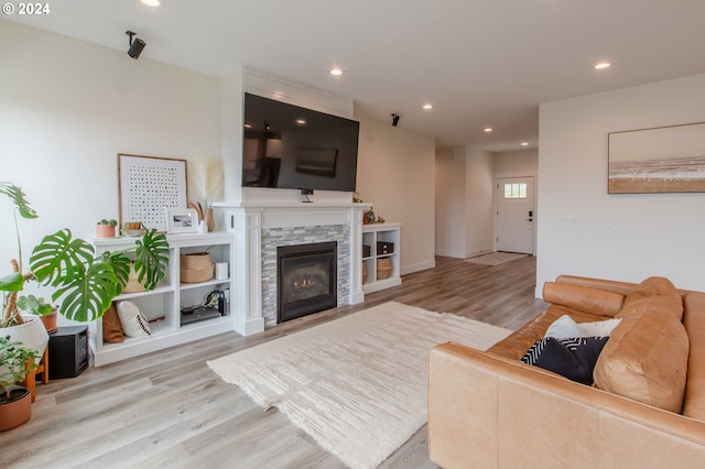 living room featuring a stone fireplace and hardwood / wood-style floors