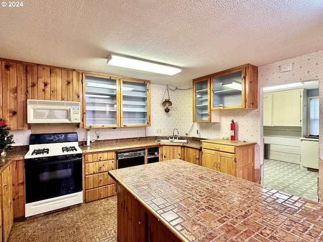 kitchen with a textured ceiling, tile countertops, sink, and white appliances