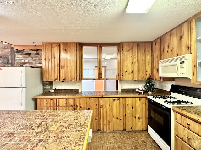 kitchen with a textured ceiling, brick wall, and white appliances