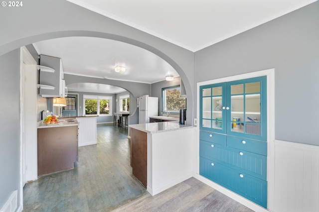 kitchen with light stone countertops, crown molding, wood-type flooring, white cabinets, and white fridge