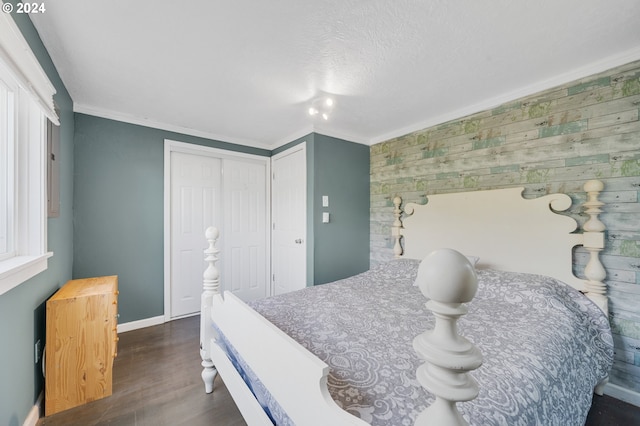 bedroom with a closet, dark wood-type flooring, a textured ceiling, and ornamental molding