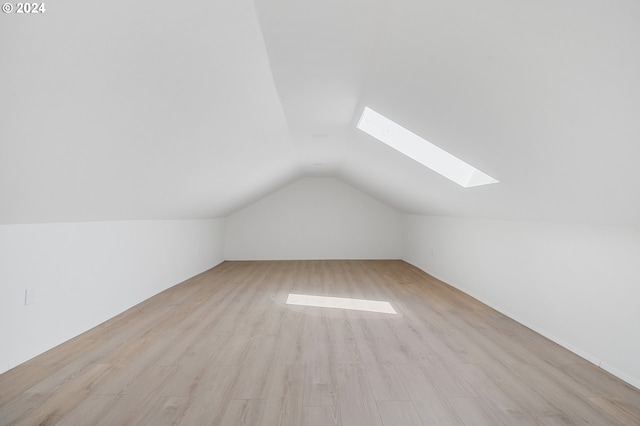 bonus room featuring vaulted ceiling with skylight and light hardwood / wood-style floors