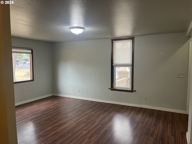 unfurnished room with a textured ceiling and dark wood-type flooring