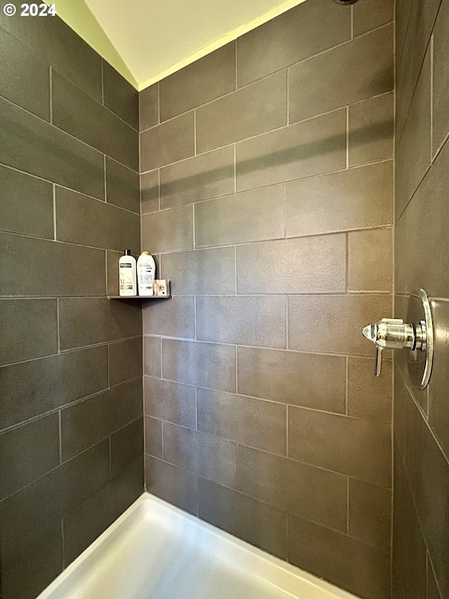 bathroom with a tile shower and vaulted ceiling