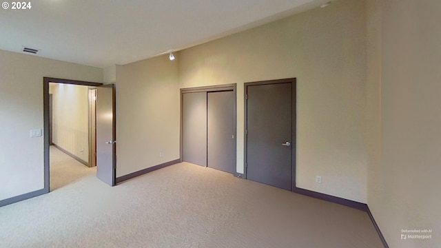 unfurnished bedroom featuring a closet and light colored carpet