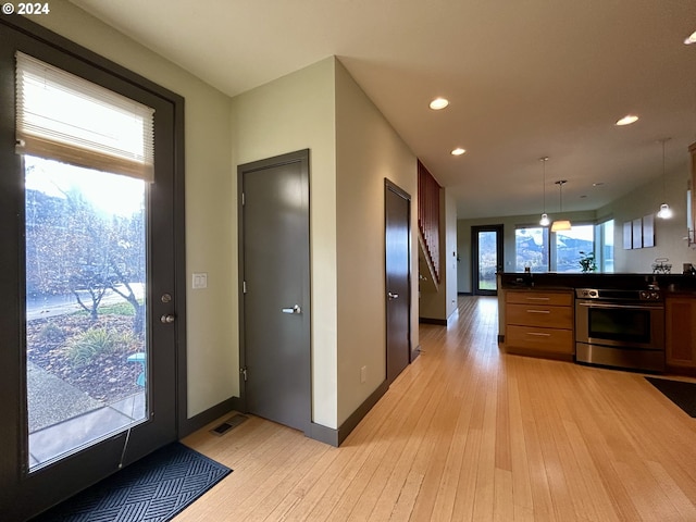 kitchen featuring pendant lighting, stainless steel range with electric stovetop, and light hardwood / wood-style floors