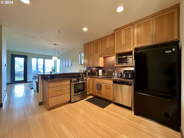 kitchen featuring pendant lighting, light wood-type flooring, kitchen peninsula, and stainless steel appliances