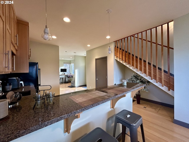 kitchen featuring kitchen peninsula, a breakfast bar, hanging light fixtures, and light hardwood / wood-style flooring