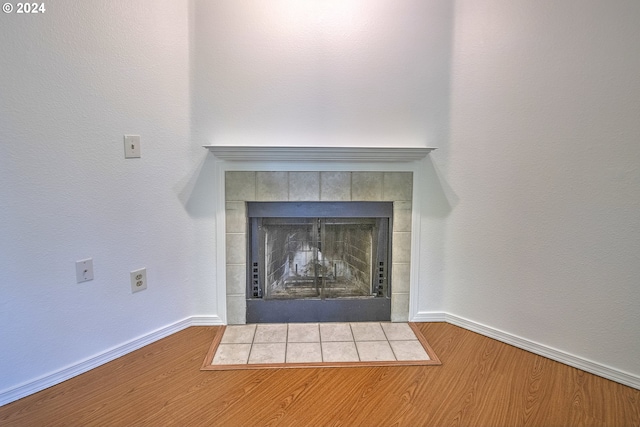 details with a tiled fireplace and wood-type flooring