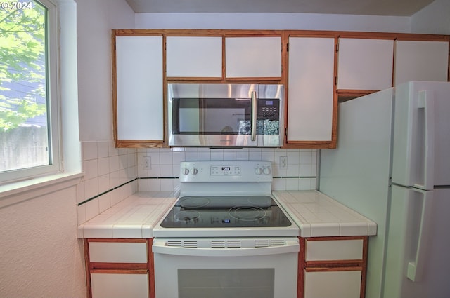 kitchen featuring white cabinetry, white appliances, and tile counters