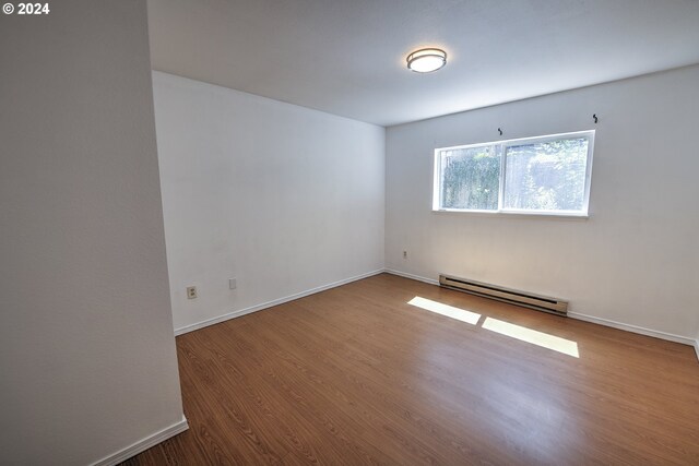 spare room with hardwood / wood-style flooring and a baseboard heating unit