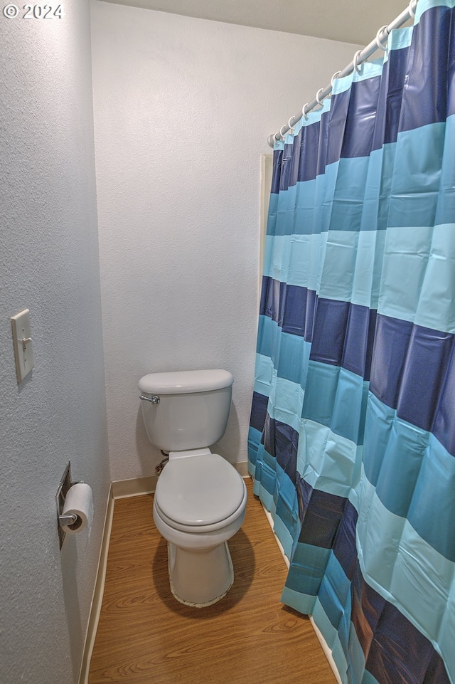 bathroom with hardwood / wood-style floors, curtained shower, and toilet