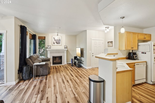 kitchen with light brown cabinets, hanging light fixtures, kitchen peninsula, light hardwood / wood-style floors, and white appliances