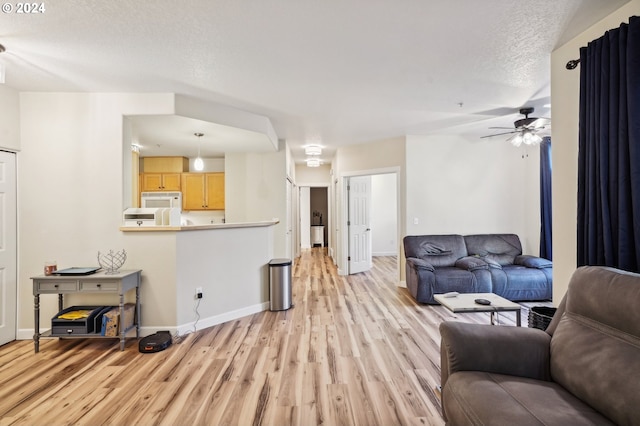 living room with a textured ceiling, light hardwood / wood-style flooring, and ceiling fan