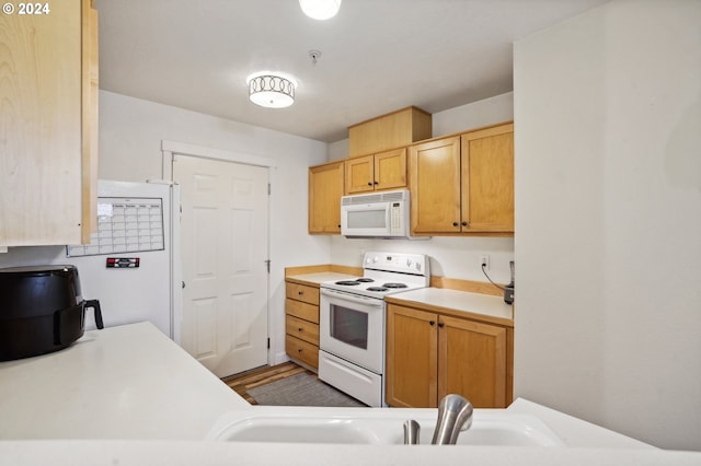 kitchen featuring light brown cabinets, white appliances, and sink