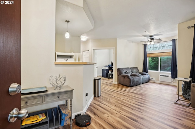 living room with light hardwood / wood-style floors, an AC wall unit, ceiling fan, and a baseboard radiator