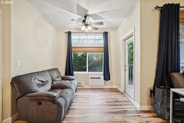 living area with ceiling fan, a baseboard heating unit, light hardwood / wood-style flooring, and a wall mounted AC