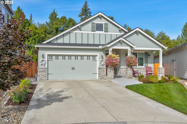 craftsman inspired home featuring stone siding, covered porch, board and batten siding, and driveway