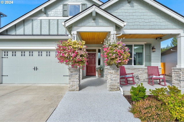 craftsman house with concrete driveway, an attached garage, covered porch, and stone siding