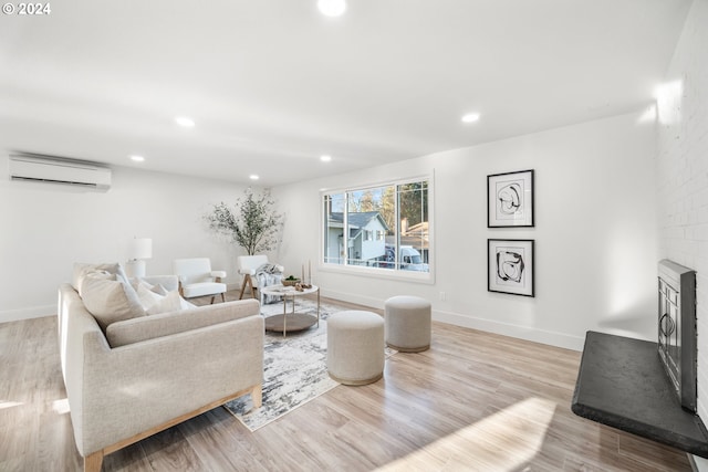 living room with a fireplace, an AC wall unit, and light hardwood / wood-style flooring