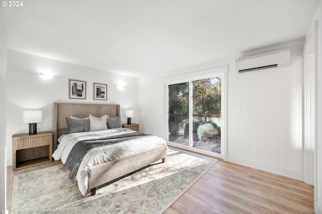 bedroom with light hardwood / wood-style flooring, access to outside, and a wall unit AC