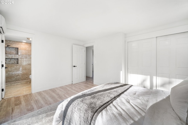 bedroom with ensuite bath, a closet, and light wood-type flooring