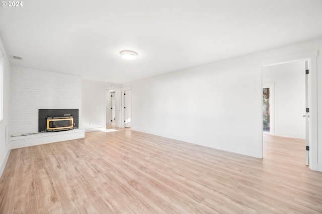 unfurnished living room with a wood stove and light hardwood / wood-style flooring