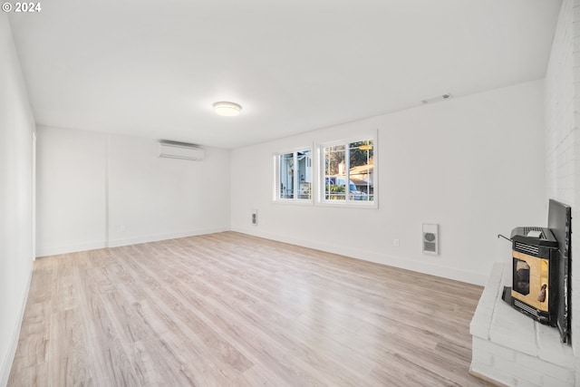 unfurnished living room featuring an AC wall unit, heating unit, and light hardwood / wood-style flooring