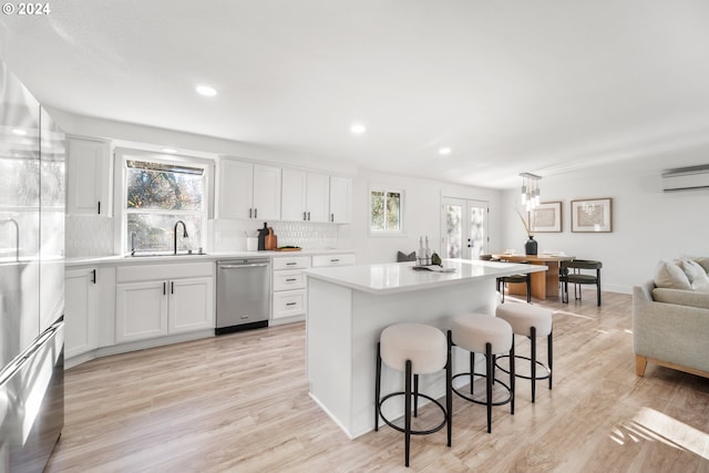 kitchen featuring sink, white cabinetry, stainless steel dishwasher, and a kitchen island