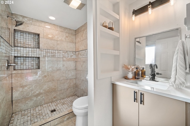 bathroom featuring tiled shower, tile patterned flooring, built in features, toilet, and vanity