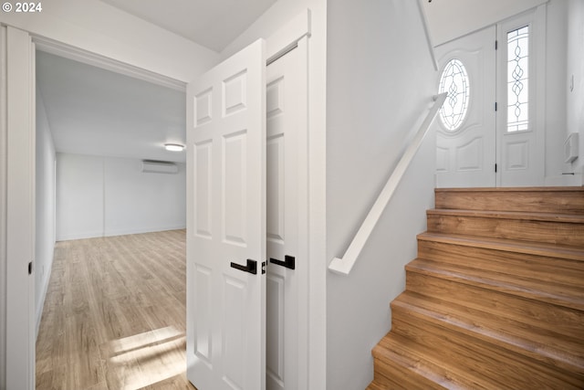 staircase featuring an AC wall unit and hardwood / wood-style floors