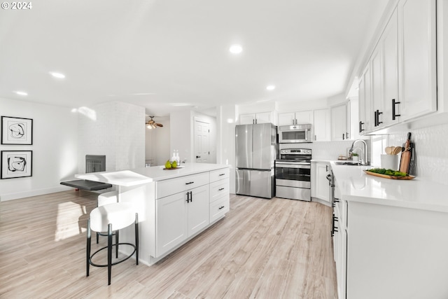 kitchen featuring appliances with stainless steel finishes, light hardwood / wood-style floors, white cabinetry, and decorative backsplash