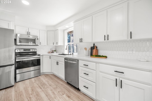 kitchen with white cabinetry, tasteful backsplash, light hardwood / wood-style floors, and appliances with stainless steel finishes