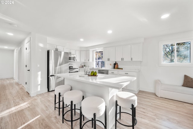 kitchen with white cabinetry, stainless steel appliances, a breakfast bar, and a kitchen island