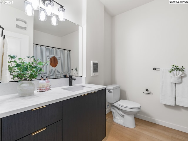 bathroom with hardwood / wood-style floors, vanity, toilet, and a chandelier