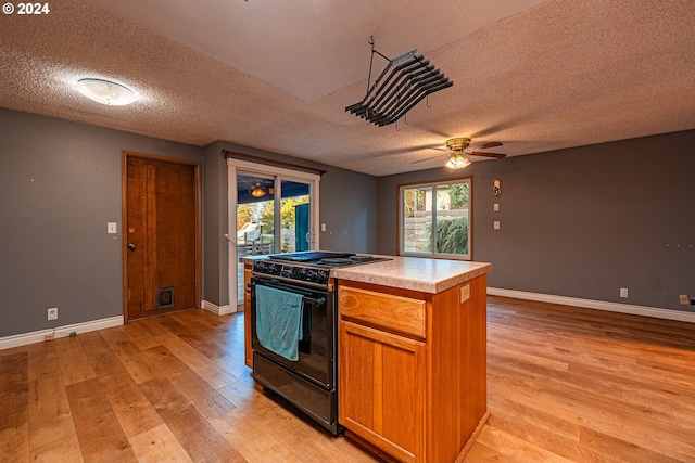 kitchen with a textured ceiling, light hardwood / wood-style flooring, and black range oven