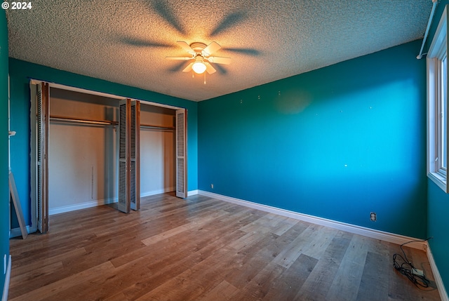 unfurnished bedroom with ceiling fan, hardwood / wood-style flooring, a textured ceiling, and multiple windows