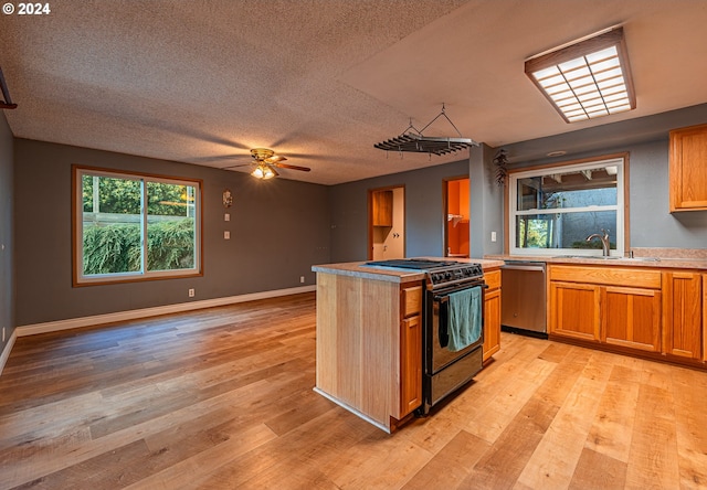 kitchen with sink, gas stove, light hardwood / wood-style floors, ceiling fan, and stainless steel dishwasher