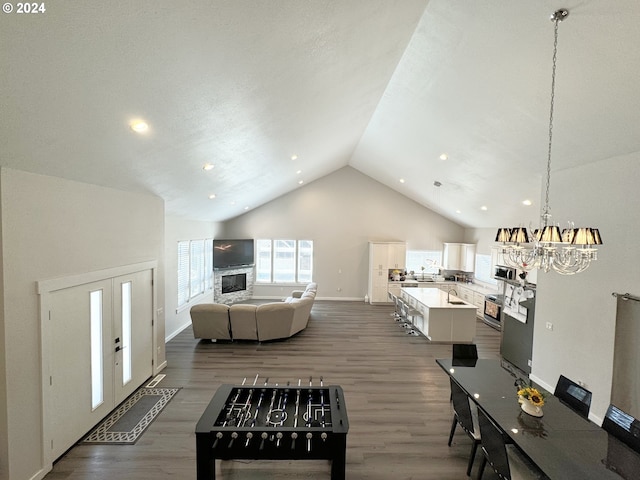 living room with a chandelier, high vaulted ceiling, and dark hardwood / wood-style flooring