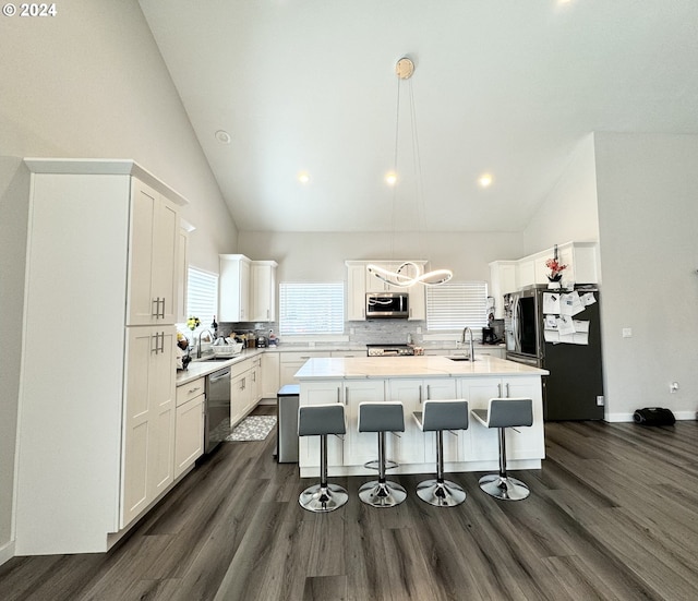 kitchen with white cabinets, decorative light fixtures, a center island with sink, and appliances with stainless steel finishes