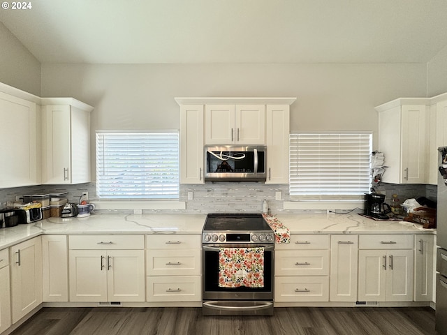 kitchen with dark hardwood / wood-style flooring, appliances with stainless steel finishes, white cabinets, light stone counters, and decorative backsplash