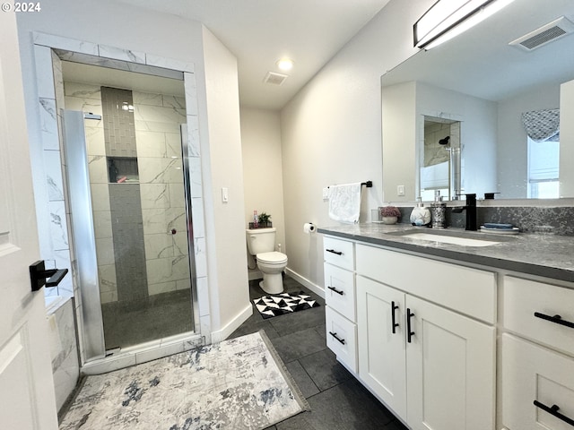 bathroom featuring vanity, a shower with shower door, and toilet